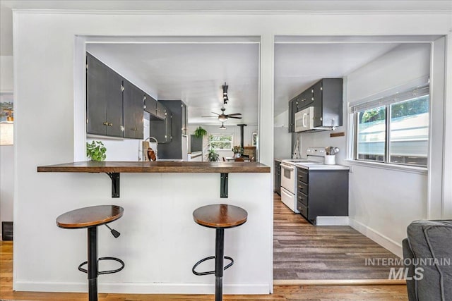 1984 11th Ave E, Twin Falls, ID 83301 - kitchen featuring white range with electric stovetop, wood finished floors, a ceiling fan, a breakfast bar, and baseboards