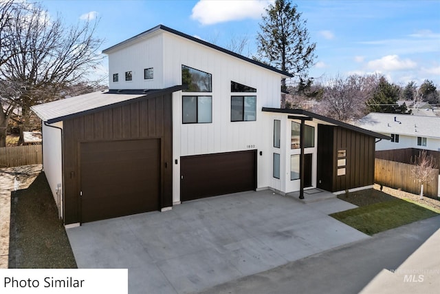 contemporary house featuring concrete driveway, fence, and a garage