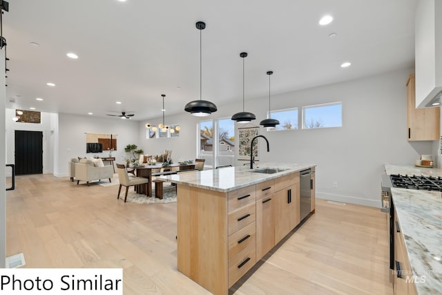 kitchen with light stone counters, light brown cabinets, a sink, light wood-style floors, and appliances with stainless steel finishes