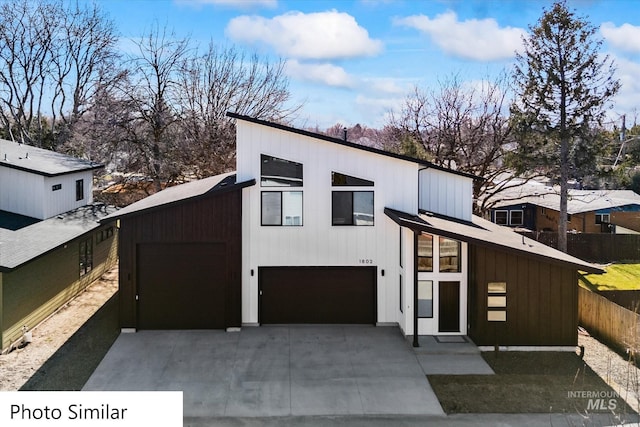 view of front of property featuring concrete driveway, a garage, and fence