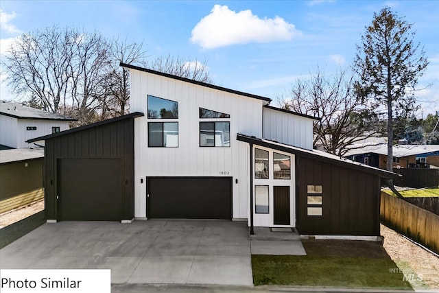 contemporary house featuring board and batten siding, concrete driveway, fence, and a garage