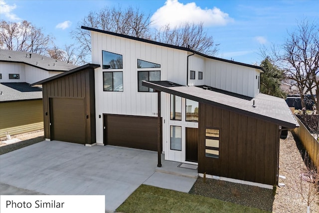 modern home with fence, board and batten siding, and driveway