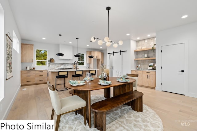 dining space with recessed lighting, a barn door, baseboards, and light wood-style flooring