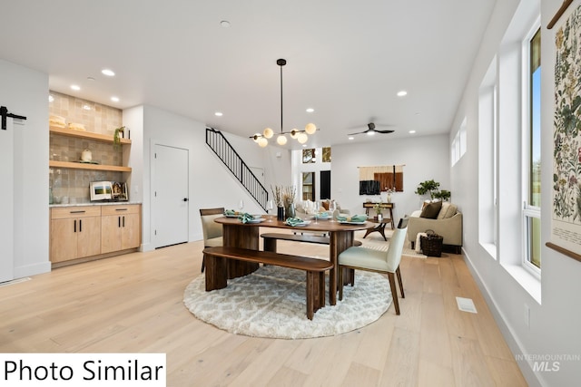 dining area featuring stairs, a barn door, recessed lighting, and light wood finished floors