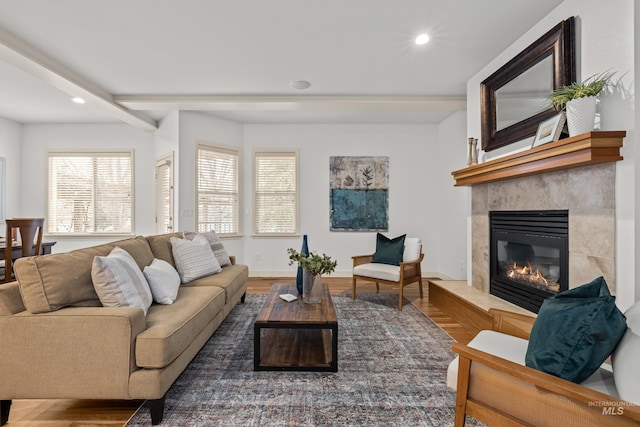 living room featuring beamed ceiling, a tiled fireplace, and hardwood / wood-style floors