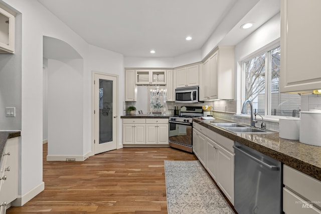 kitchen featuring appliances with stainless steel finishes, tasteful backsplash, white cabinetry, sink, and light hardwood / wood-style flooring