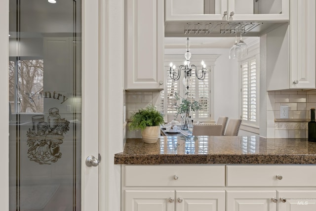 kitchen with tasteful backsplash, pendant lighting, dark stone counters, and white cabinets