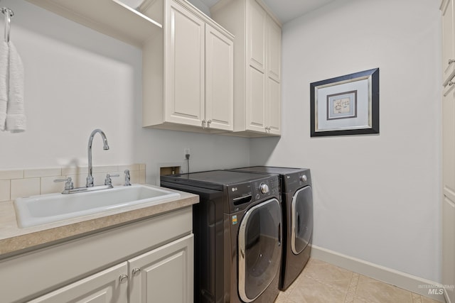 laundry area with cabinets, light tile patterned floors, sink, and washing machine and clothes dryer