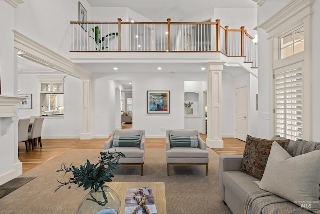 living room with a towering ceiling, decorative columns, and hardwood / wood-style floors