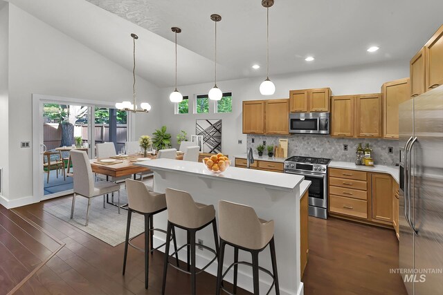3742 N Heritage View Ave, Meridian, ID 83646 - kitchen featuring appliances with stainless steel finishes, light countertops, tasteful backsplash, dark wood-style flooring, and a kitchen breakfast bar