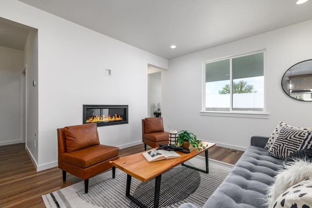 living area with visible vents, wood finished floors, a glass covered fireplace, recessed lighting, and baseboards