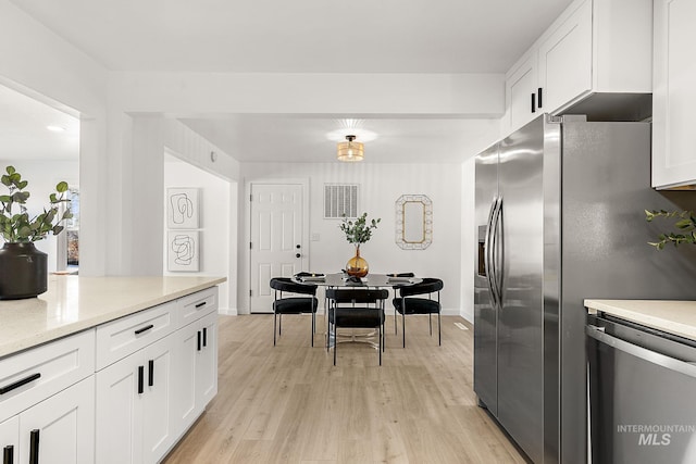 kitchen featuring appliances with stainless steel finishes, light stone countertops, light wood-type flooring, and white cabinets