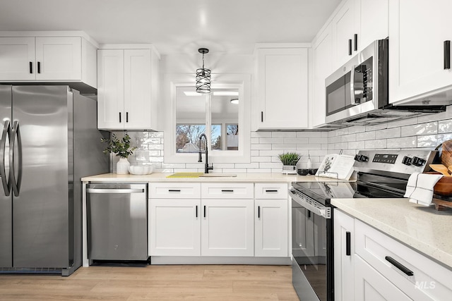 kitchen featuring pendant lighting, stainless steel appliances, and white cabinets