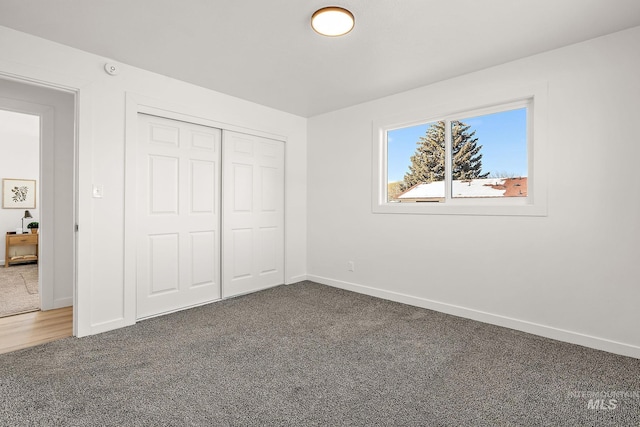 unfurnished bedroom with dark carpet and a closet