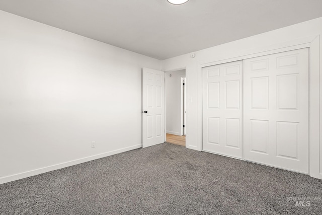 unfurnished bedroom with dark carpet and a closet