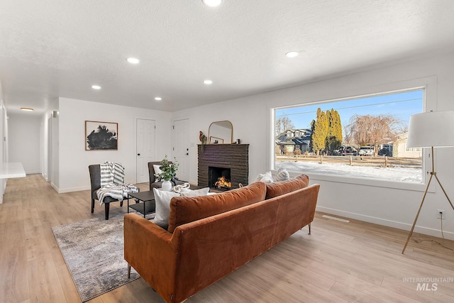 living room featuring a fireplace, light hardwood / wood-style flooring, and a textured ceiling