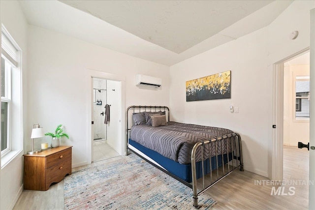 bedroom with multiple windows, a wall mounted air conditioner, and light wood-type flooring