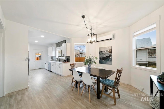 dining area with a chandelier, light hardwood / wood-style floors, a wall mounted air conditioner, and sink