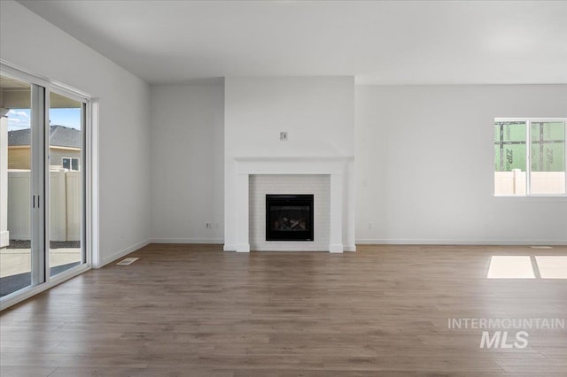 5278 W Mcnair St, Meridian, ID 83646 - unfurnished living room featuring healthy amount of natural light, wood finished floors, baseboards, and a brick fireplace