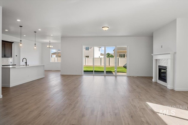 5278 W Mcnair St, Meridian, ID 83646 - unfurnished living room with recessed lighting, a fireplace, baseboards, light wood-style floors, and a sink