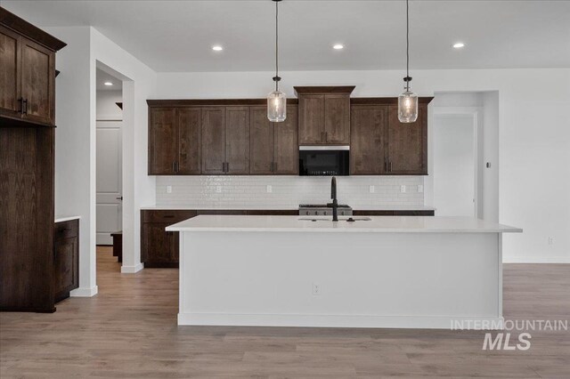 5278 W Mcnair St, Meridian, ID 83646 - kitchen with black microwave, dark brown cabinets, decorative backsplash, light wood finished floors, and recessed lighting