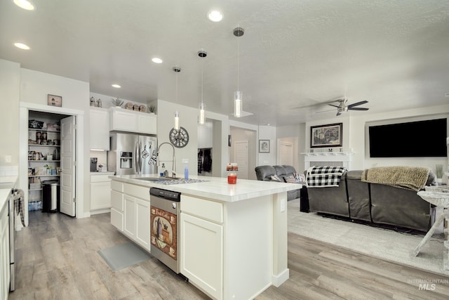 2982 W Mcintosh, Kuna, ID 83634 - kitchen featuring stainless steel appliances, light wood finished floors, a ceiling fan, open floor plan, and light countertops