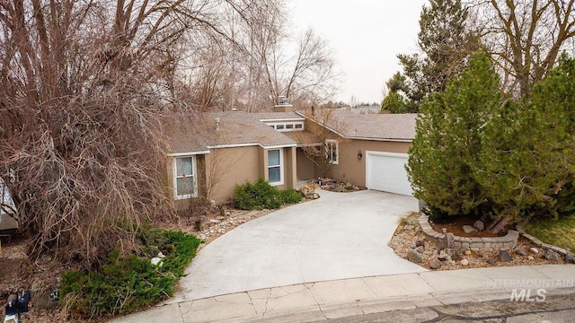 view of front of home with a garage, driveway, a chimney, and stucco siding