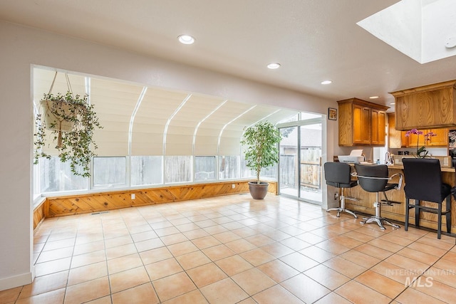 kitchen with light tile patterned floors, a kitchen breakfast bar, brown cabinetry, and recessed lighting