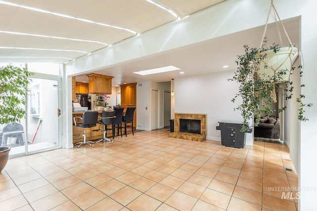 living area featuring visible vents, a tiled fireplace, and light tile patterned floors