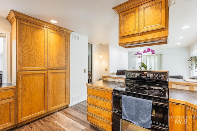 kitchen with range with two ovens, brown cabinetry, and visible vents