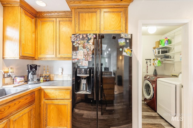 kitchen featuring a sink, washer and dryer, light countertops, black fridge, and brown cabinets