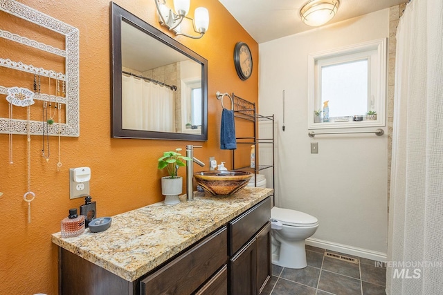 bathroom featuring visible vents, toilet, vanity, baseboards, and tile patterned floors