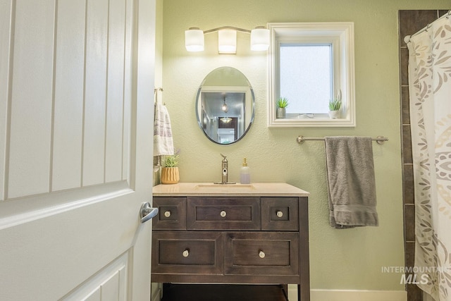 full bathroom with a textured wall and vanity