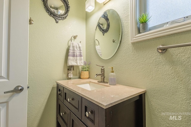 bathroom with a textured wall and vanity