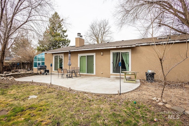 rear view of property with a patio, a chimney, and stucco siding