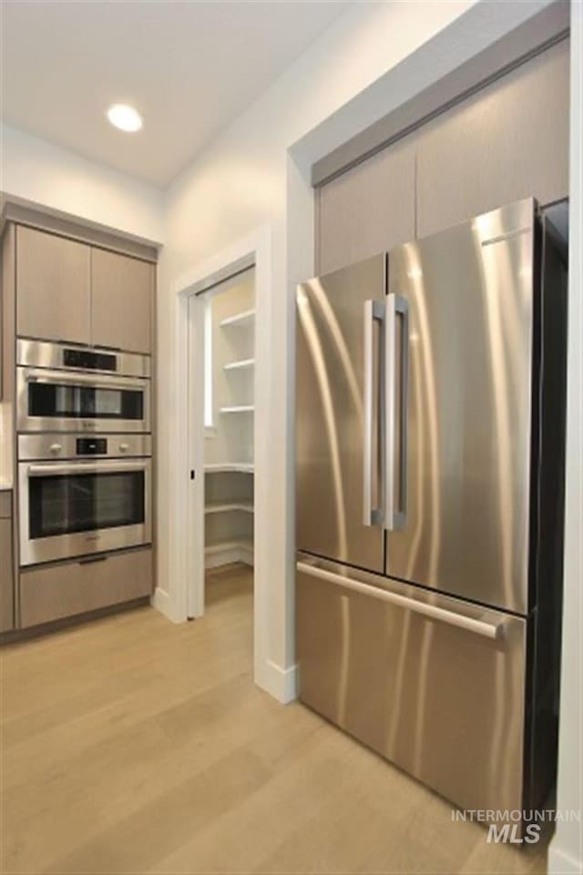 kitchen with appliances with stainless steel finishes and light hardwood / wood-style flooring