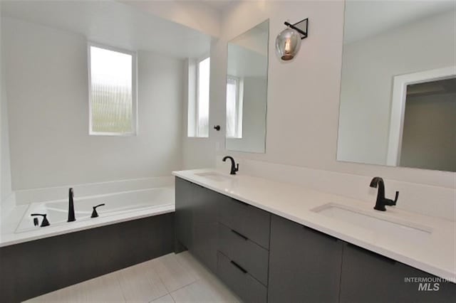 bathroom with a tub to relax in, tile patterned flooring, and vanity