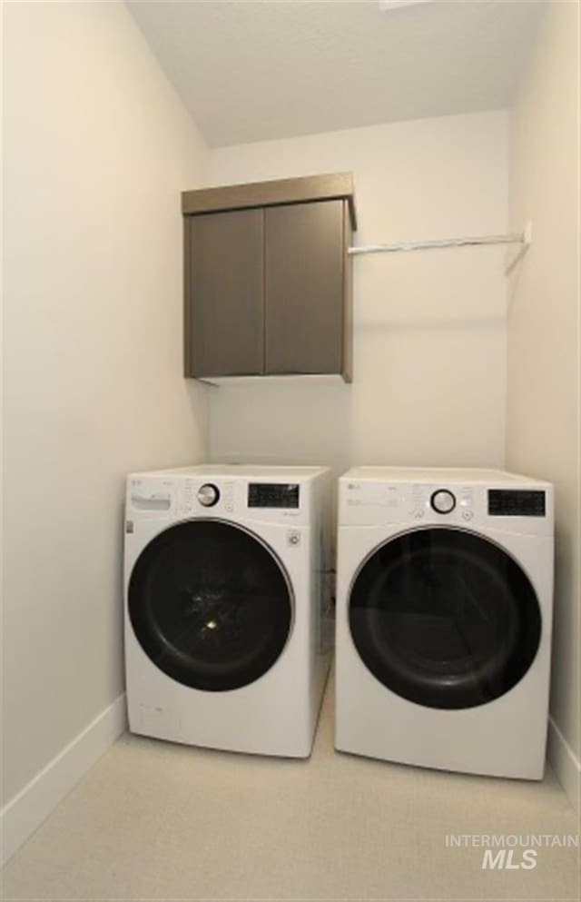 washroom featuring washer and clothes dryer, cabinets, and light carpet