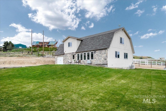 8618 Latimore Ln, Middleton, ID 83644 - rear view of house with a gambrel roof, board and batten siding, stone siding, a shingled roof, and cooling unit