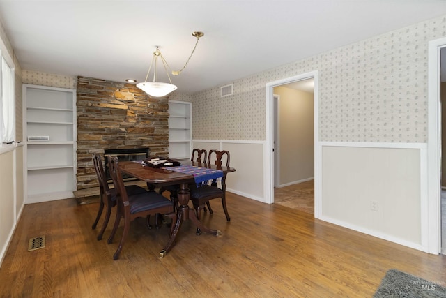 1719 S Gekeler Ln, Boise, ID 83706 - dining area with wainscoting, wallpapered walls, wood finished floors, and a stone fireplace