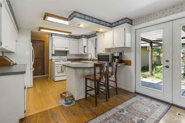 1719 S Gekeler Ln, Boise, ID 83706 - kitchen featuring gas range gas stove, a peninsula, under cabinet range hood, stainless steel microwave, and dark countertops