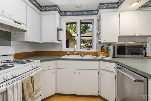 1719 S Gekeler Ln, Boise, ID 83706 - kitchen featuring stainless steel appliances, a sink, under cabinet range hood, white cabinetry, and dark countertops