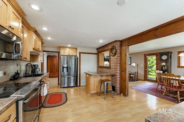 10838 W Southerland St, Boise, ID 83709 - kitchen featuring a textured ceiling, a sink, light wood finished floors, appliances with stainless steel finishes, and backsplash