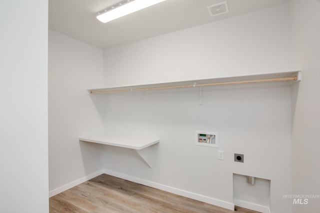 laundry area featuring electric dryer hookup, hookup for a washing machine, and light hardwood / wood-style flooring