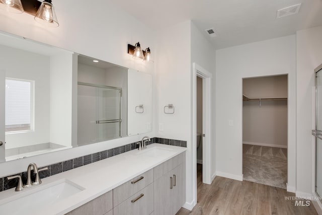 bathroom with hardwood / wood-style floors, vanity, toilet, and a shower with door