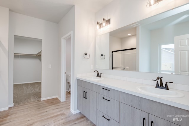 bathroom with walk in shower, hardwood / wood-style floors, vanity, and toilet