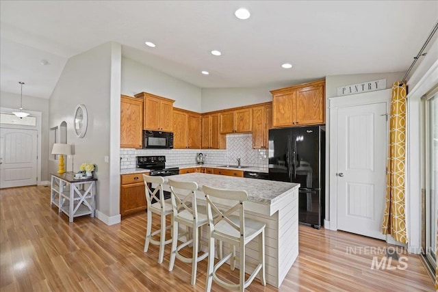 1879 Prairie View Way, Middleton, ID 83644 - kitchen featuring black appliances, vaulted ceiling, decorative backsplash, a kitchen island, and a kitchen bar