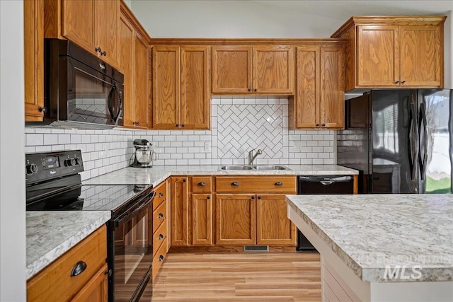 1879 Prairie View Way, Middleton, ID 83644 - kitchen featuring black appliances, a sink, light wood finished floors, brown cabinetry, and vaulted ceiling