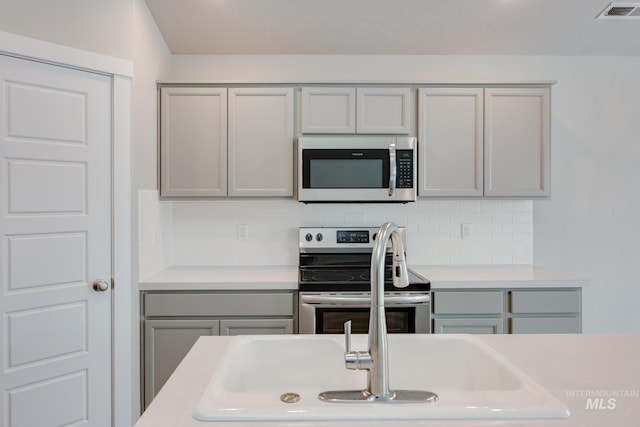 kitchen featuring gray cabinetry, stainless steel appliances, and decorative backsplash