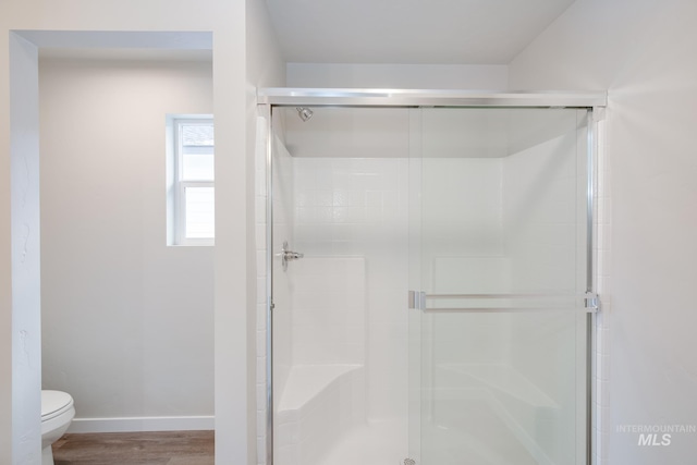 bathroom featuring an enclosed shower, wood-type flooring, and toilet